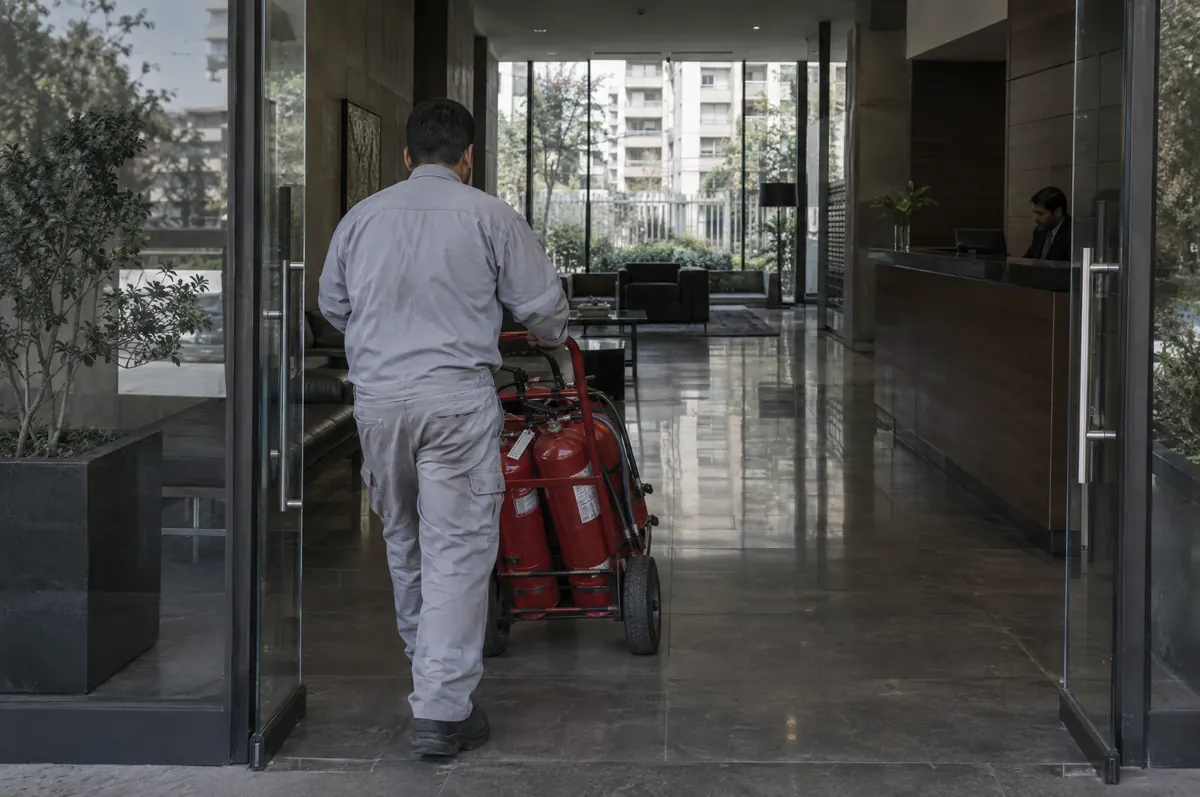 Técnico de otra empresa entrando con un carro de extintores al hall de un edificio